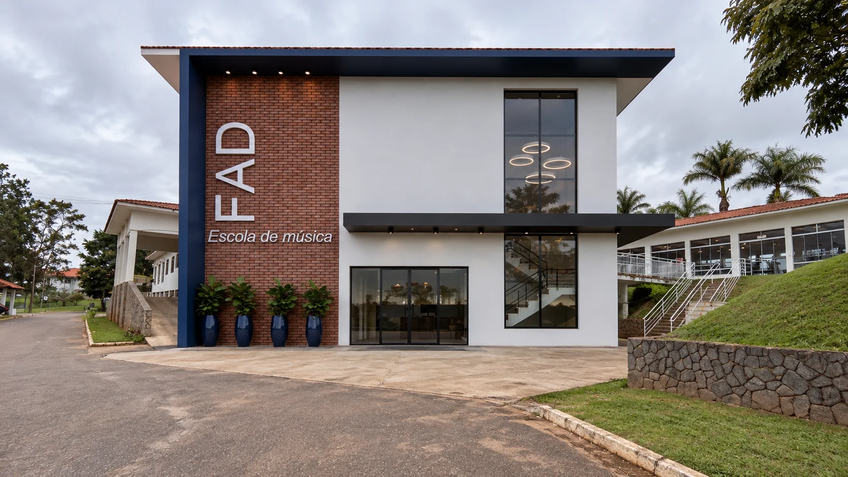 Fachada de edifício escolar com volume branco e letreiro vertical